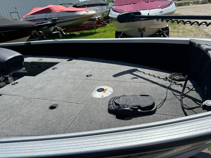 Slide: The Image of 2023 Alumacraft Competitor 185 Tiller boat interior with carpeted deck and trolling motor. - 17