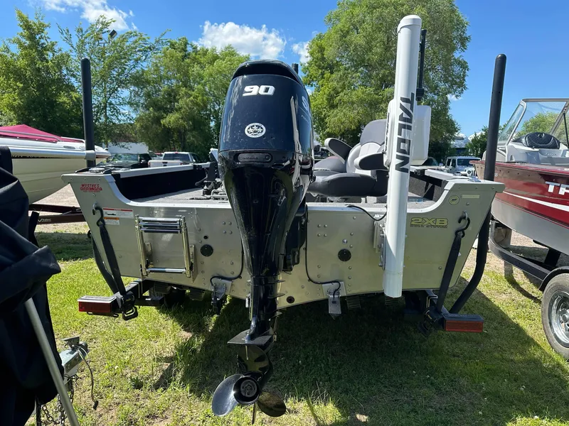 Slide: The Image of 2023 Alumacraft Competitor 185 Tiller boat with outboard motor, parked on grass. - 20
