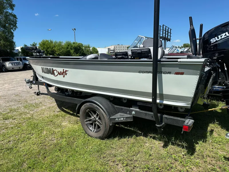 Slide: The Image of 2023 Alumacraft Competitor 185 Tiller boat on trailer, parked outdoors. - 30
