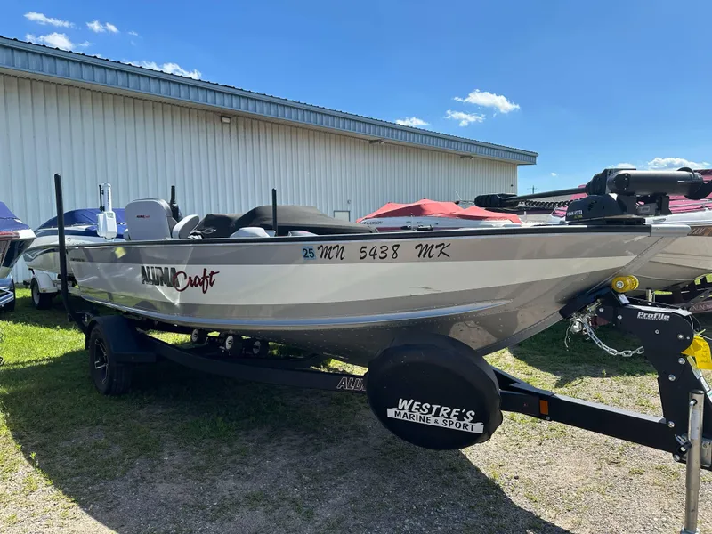Slide: The Image of 2023 Alumacraft Competitor 185 Tiller boat on trailer, parked outdoors. - 33