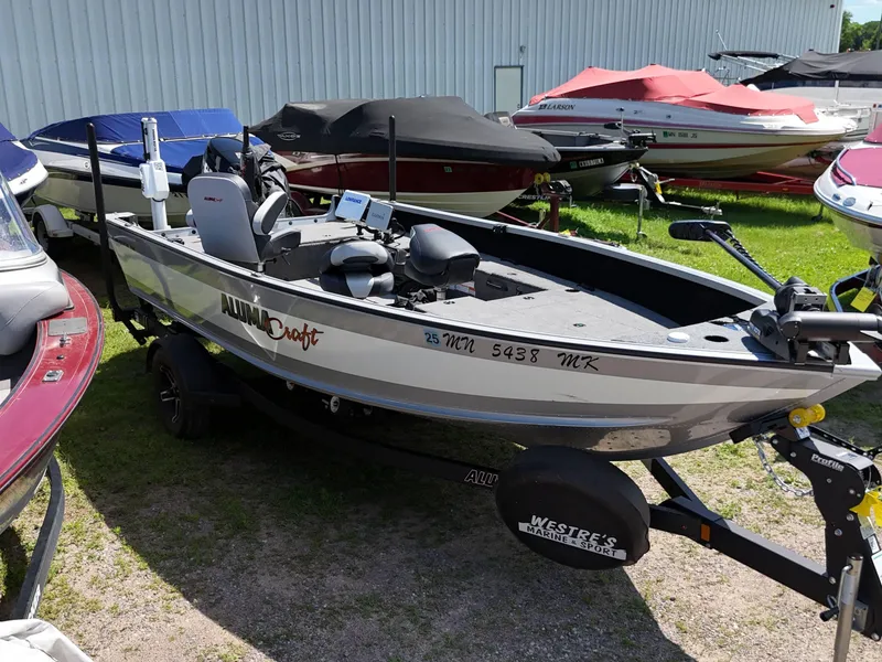 Slide: The Image of 2023 Alumacraft Competitor 185 Tiller boat on trailer, parked outdoors. - 4