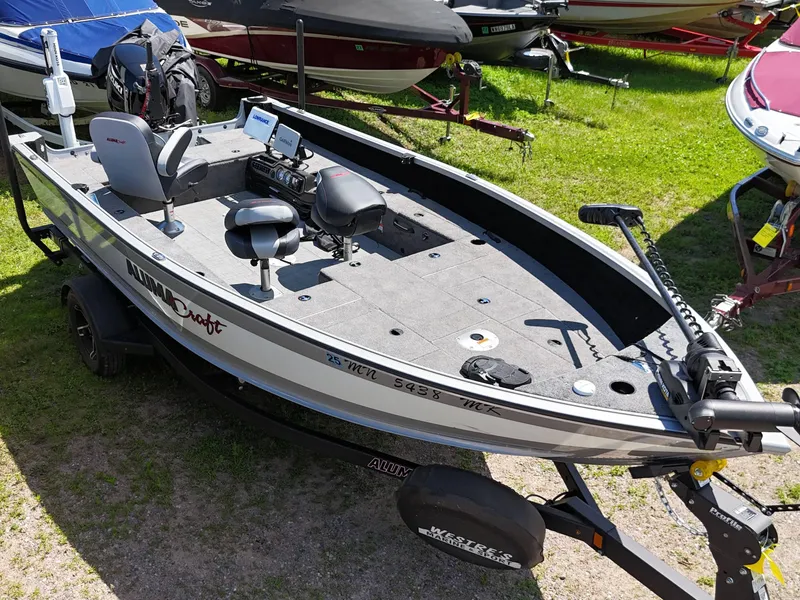 Slide: The Image of 2023 Alumacraft Competitor 185 Tiller boat on trailer, parked on grass. - 5