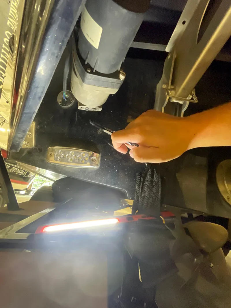 Slide: The Image of Hand adjusting component under 2022 Malibu Wakesetter 23 LSV boat with visible light and propeller. - 4