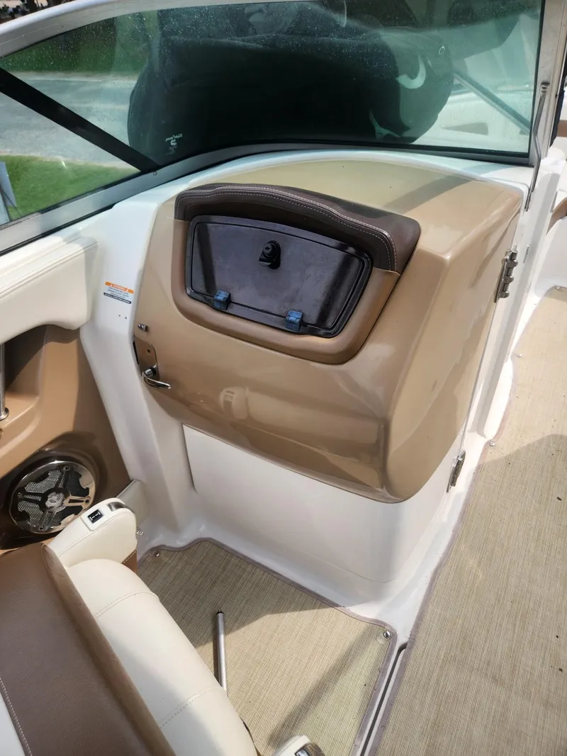 Slide: The Image of 2016 Chaparral 246 SSi boat interior with beige and white seating, storage compartment, and speaker. - 14