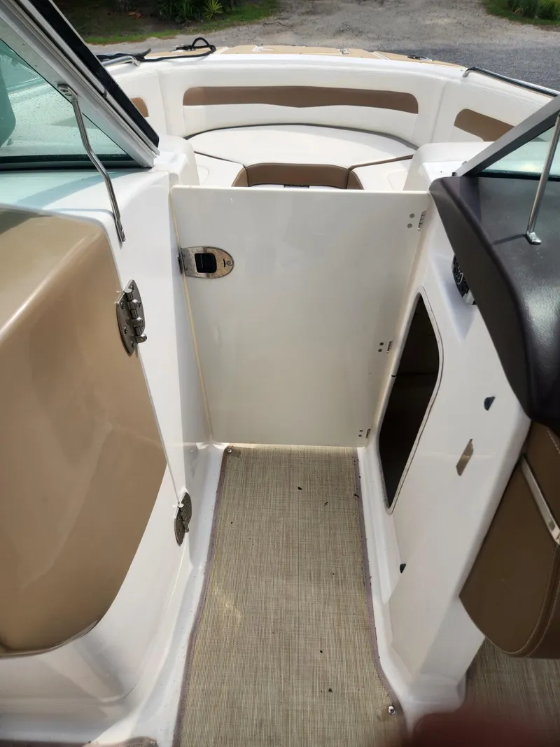 Slide: The Image of Interior view of a 2016 Chaparral 246 SSi boat, featuring seating and a small door. - 16