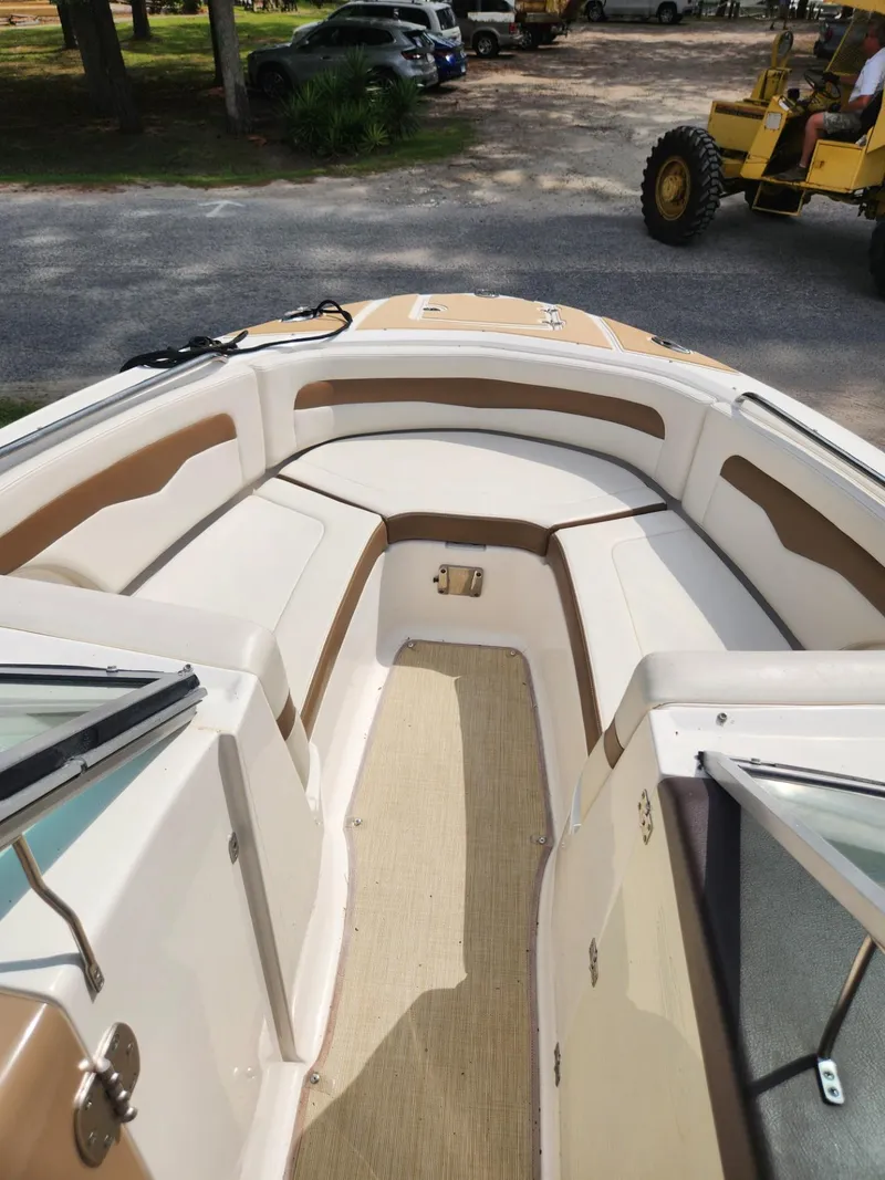 Slide: The Image of 2016 Chaparral 246 SSi boat interior with tan and white seating, parked outdoors. - 19