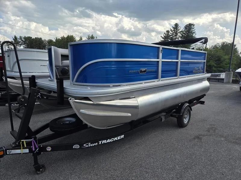 Slide: The Image of 2026 Sun Tracker PB 16 DLX pontoon boat on trailer, blue exterior, parked outdoors. - 3