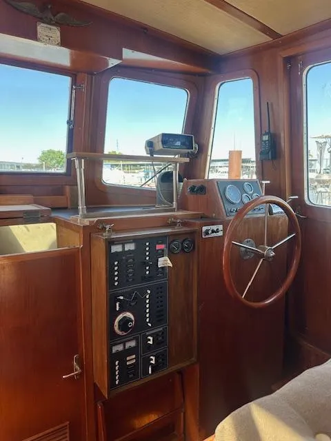 Slide: The Image of 1985 Eagle Trawler helm with wooden steering wheel and control panel, docked at marina. - 13