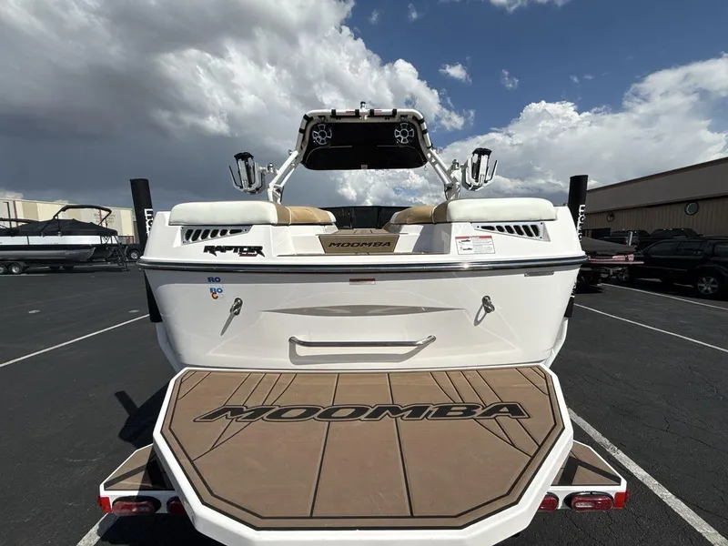 Slide: The Image of 2021 Moomba Mojo boat rear view with swim platform, parked under cloudy sky. - 4