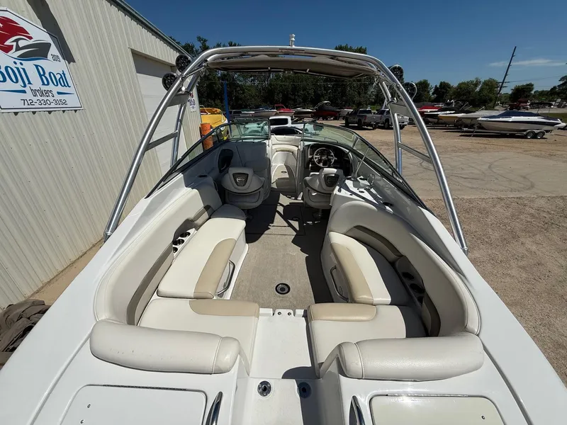 Slide: The Image of 2009 Crownline 270 BR boat interior with beige seating and steering wheel, parked outdoors. - 10