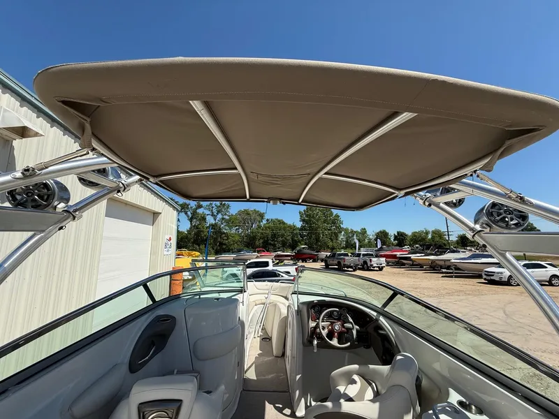 Slide: The Image of 2009 Crownline 270 BR boat interior with canopy, steering wheel, and seating under clear blue sky. - 11