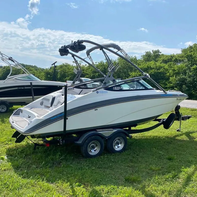 The Image of 2015 Yamaha Boats 212X on trailer, parked on grass under a clear sky. - 1