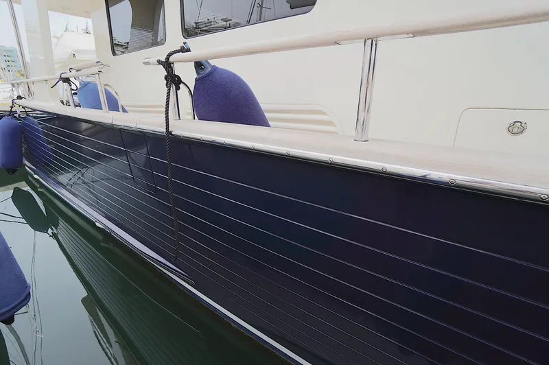 Slide: The Image of Side view of a 2009 Marlow 61E yacht with blue hull and docked fenders. - 10