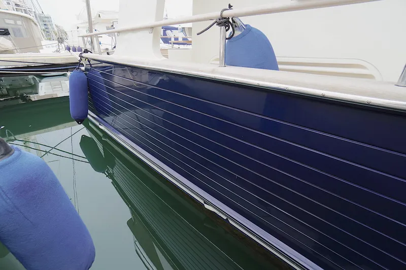 Slide: The Image of Side view of a 2009 Marlow 61E yacht with blue fenders in a marina. - 6