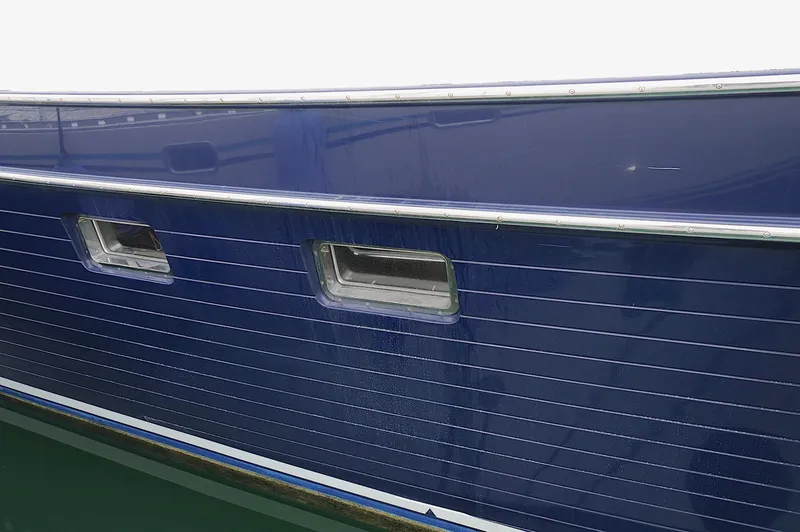 Slide: The Image of Close-up of a 2009 Marlow 61E yacht's blue hull with windows. - 8