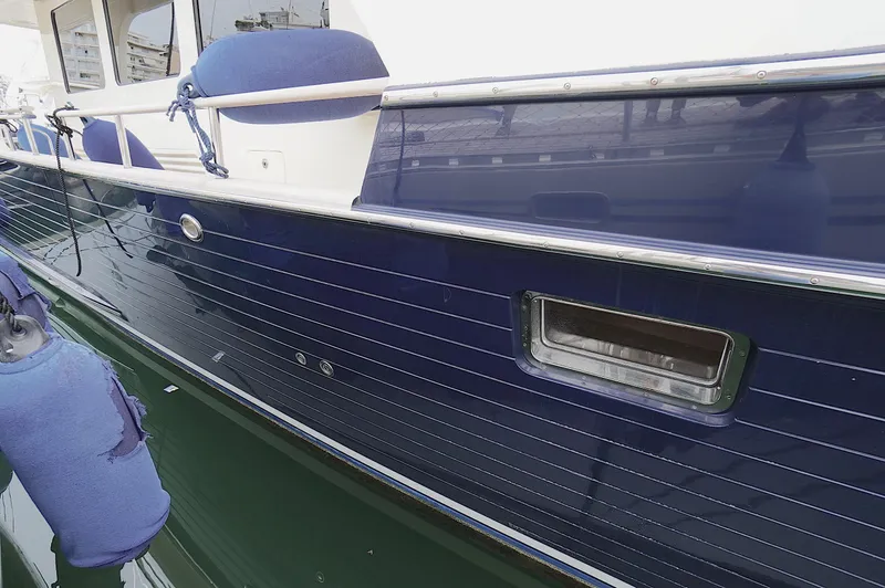 Slide: The Image of Side view of a 2009 Marlow 61E yacht with blue hull and fenders. - 9