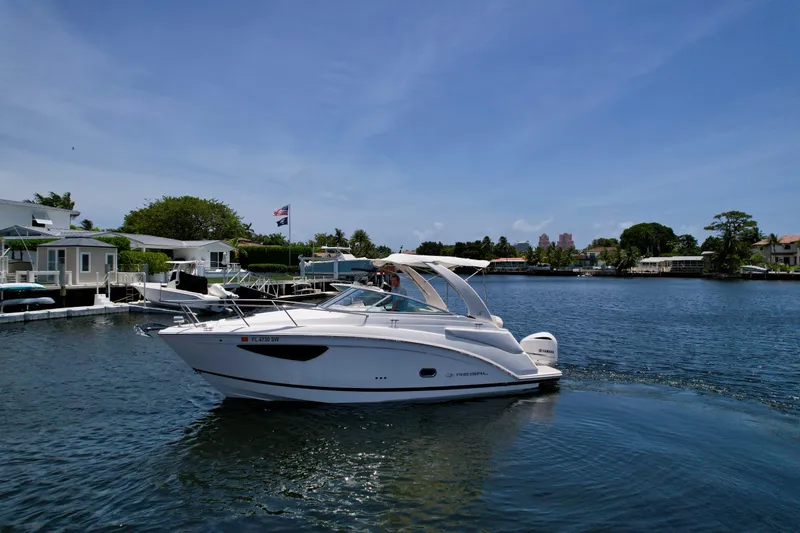 Slide: The Image of 2021 Regal 26 XO boat cruising on a sunny day near waterfront homes. - 1