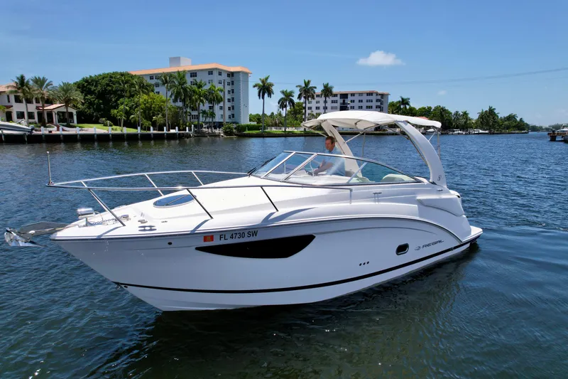 Slide: The Image of 2021 Regal 26 XO boat cruising on a sunny day near waterfront buildings. - 10