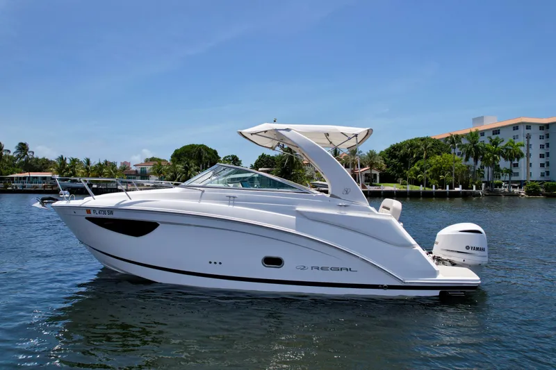Slide: The Image of 2021 Regal 26 XO boat on calm water, with a Yamaha outboard motor, under clear blue sky. - 11