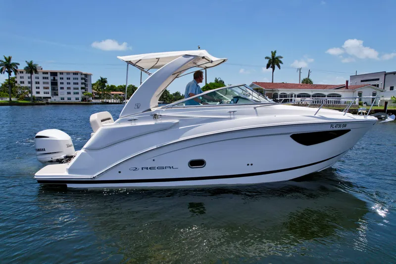 Slide: The Image of 2021 Regal 26 XO boat cruising on a sunny day, featuring a sleek white design. - 12