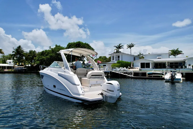 Slide: The Image of 2021 Regal 26 XO boat cruising near waterfront homes under a clear blue sky. - 14