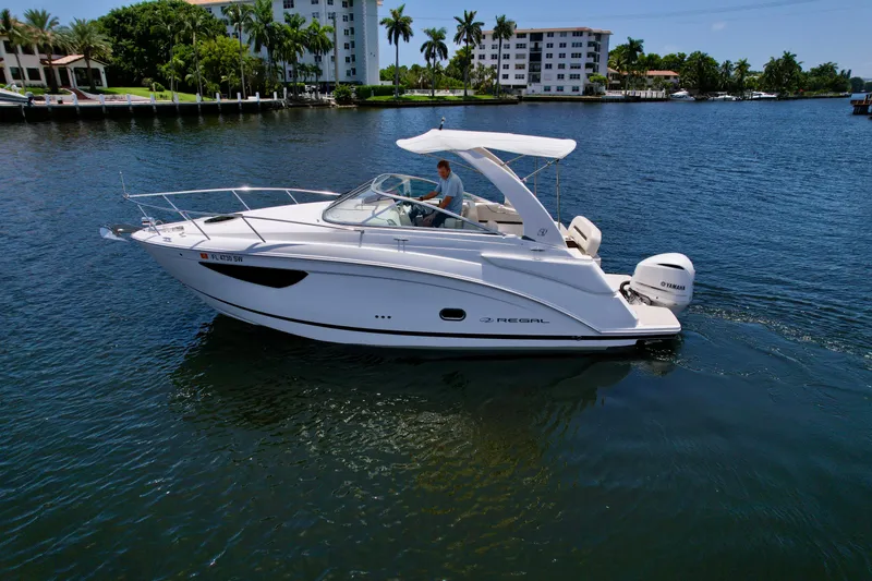 Slide: The Image of 2021 Regal 26 XO boat cruising on a sunny day in a scenic waterfront area. - 17