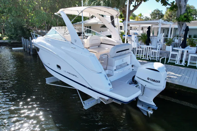 Slide: The Image of 2021 Regal 26 XO boat docked with Yamaha outboard motor, surrounded by lush greenery. - 21