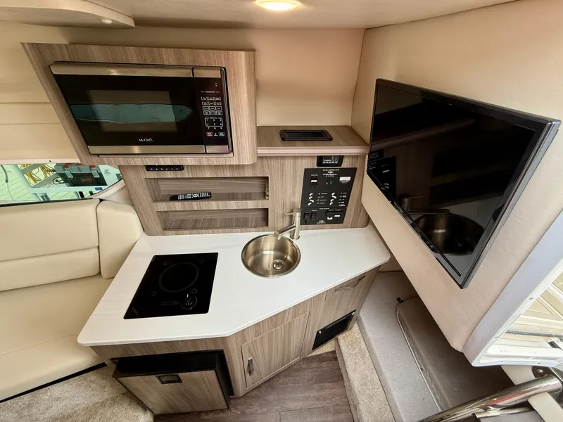 Slide: The Image of 2021 Regal 26 XO boat interior with kitchenette, microwave, sink, and TV. - 47