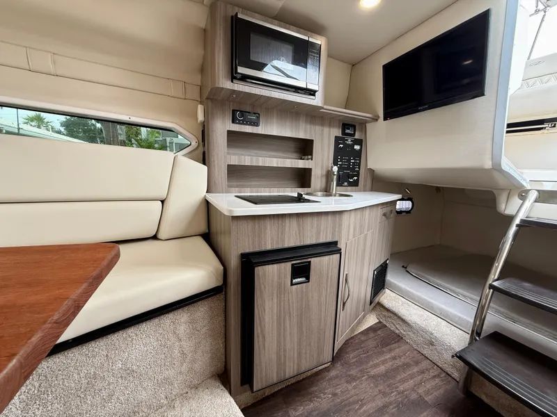 Slide: The Image of Interior of 2021 Regal 26 XO boat featuring kitchenette, seating, and modern amenities. - 55