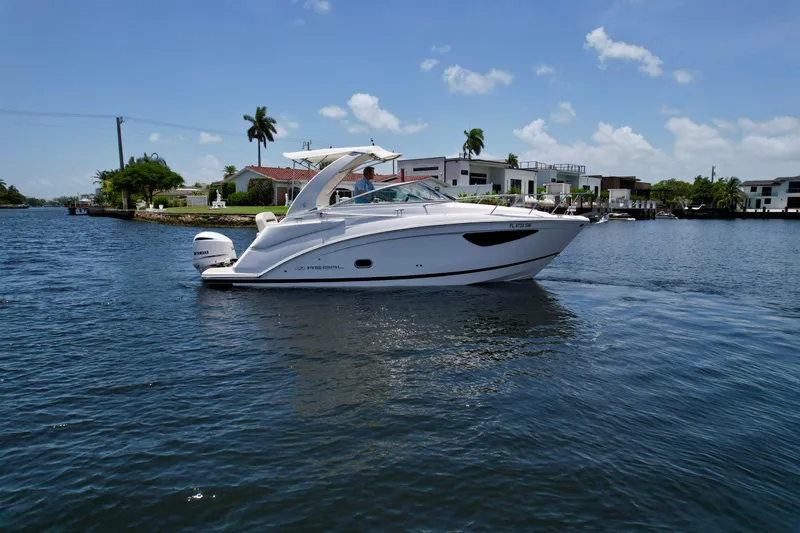 Slide: The Image of 2021 Regal 26 XO boat cruising on a sunny day near waterfront homes. - 7