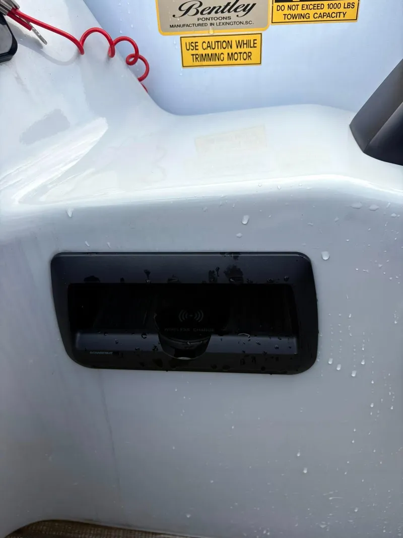 Slide: The Image of 2024 Bentley Pontoons Legacy QSB dashboard with caution labels and wet surface. - 8