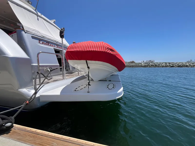 Slide: The Image of Astondoa 95GLX yacht with a red-covered boat on deck, docked by the water. - 6