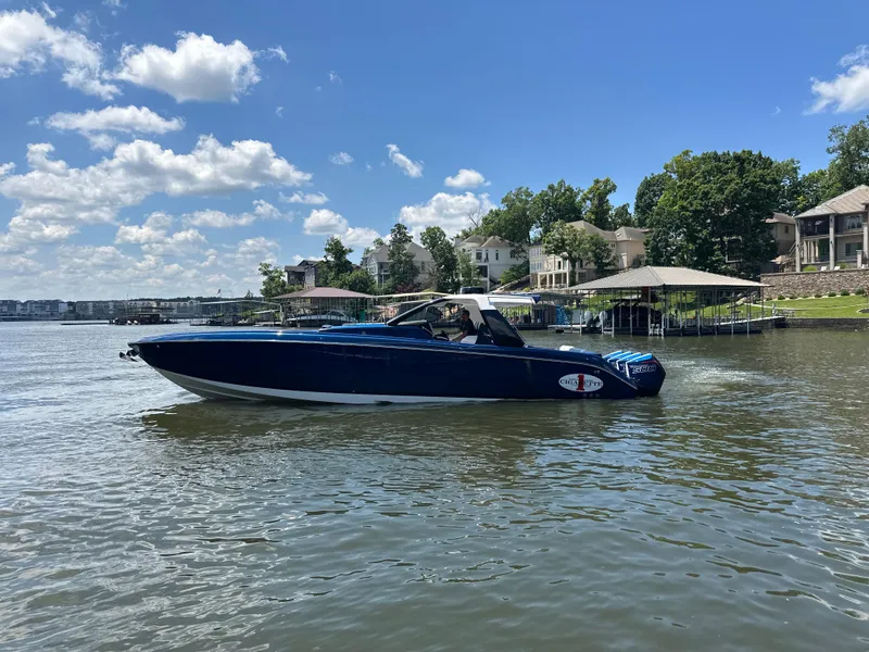 The Image of 2024 Cigarette 42 Auroris boat cruising on a sunny lake with waterfront homes. - 0