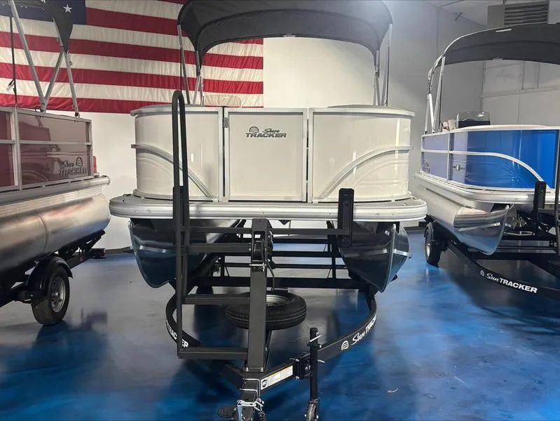 Slide: The Image of 2026 Sun Tracker PB 16 DLX pontoon boat in showroom with American flag backdrop. - 10