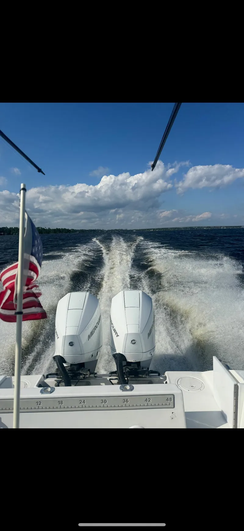 Slide: The Image of 2007 SeaCraft 25 boat cruising with twin engines, American flag, and ocean wake. - 6