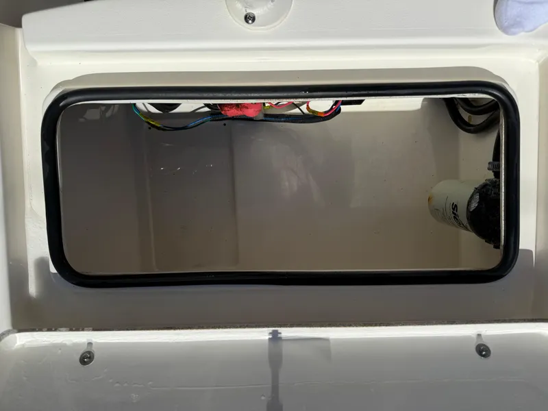 Slide: The Image of Open storage compartment in a 2015 Hewes Redfisher 18 boat, showing wiring and filter. - 18