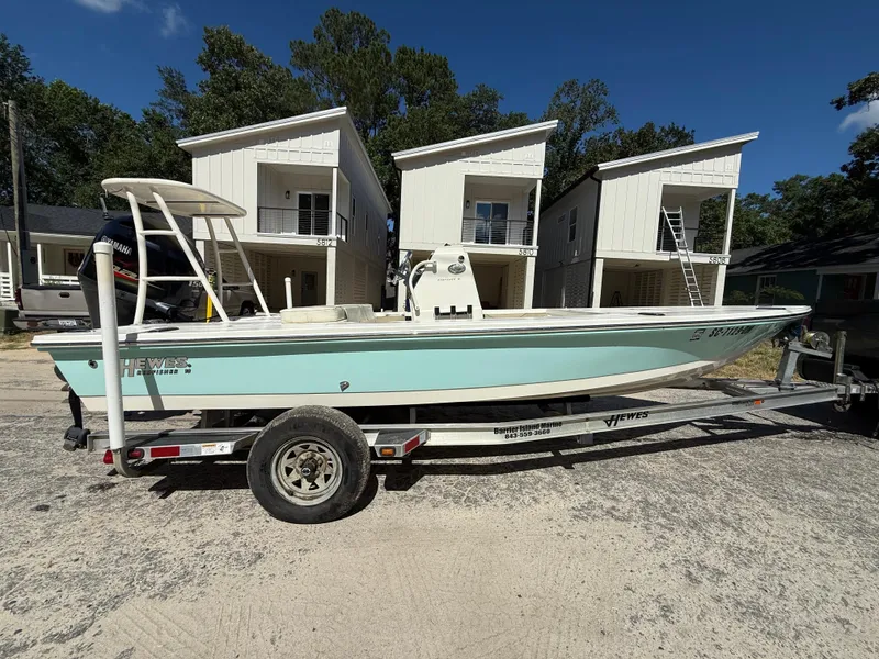 Slide: The Image of 2015 Hewes Redfisher 18 boat on trailer, parked in front of modern houses. - 2