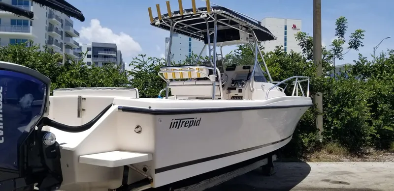 Slide: The Image of 1993 Intrepid 26 Walkaround boat with canopy, parked outdoors near buildings and greenery. - 16