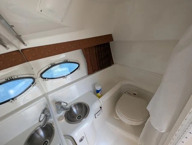 Slide: The Image of 2003 Formula 330 SS boat bathroom with sink, toilet, and porthole windows. - 13