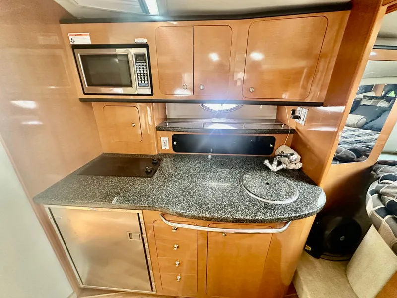 Slide: The Image of 2008 Chaparral 350 Signature yacht kitchen with microwave, stove, and sleek cabinetry. - 9