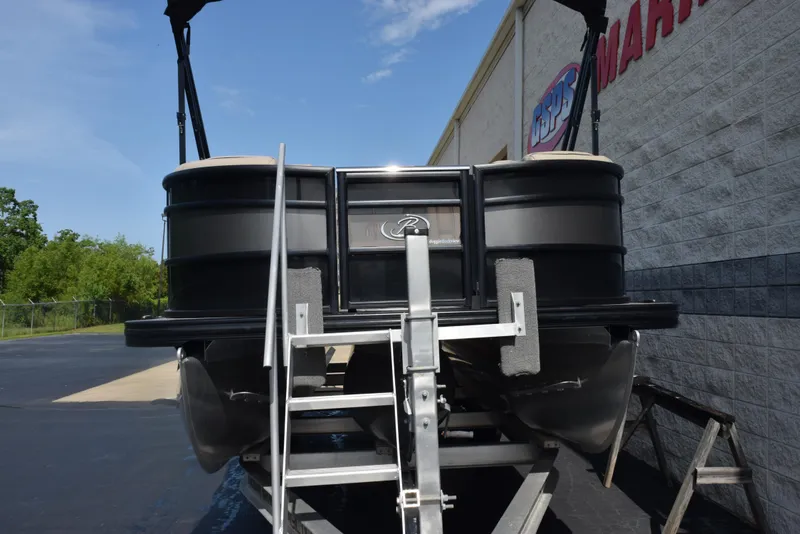 Slide: The Image of 2022 Barletta L25UC pontoon boat on trailer, parked outside a marine dealership. - 3