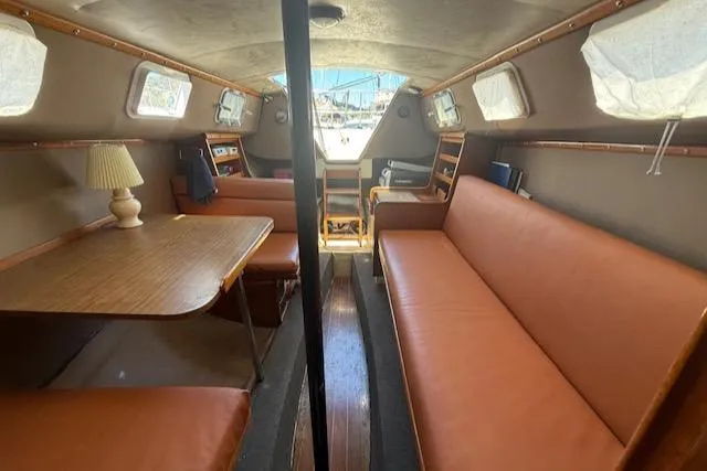 Slide: The Image of 1979 Lancer Sloop interior with brown seating, wooden table, and nautical decor. - 13