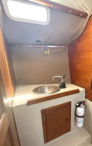 Slide: The Image of 1979 Lancer Sloop interior with sink, wooden cabinet, and fire extinguisher. - 22