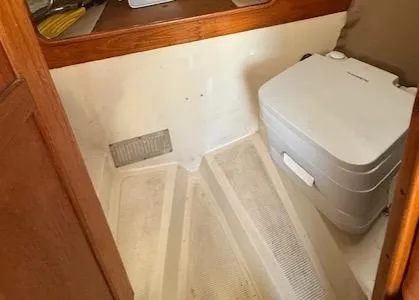 Slide: The Image of 1979 Lancer Sloop interior with compact portable toilet and wooden accents. - 23