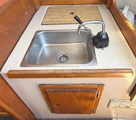 Slide: The Image of 1979 Lancer Sloop kitchen sink with wooden cabinetry and faucet. - 24