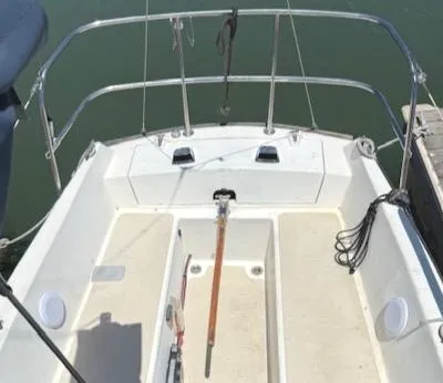 Slide: The Image of 1979 Lancer Sloop boat deck with steering tiller and railing, docked on calm water. - 8