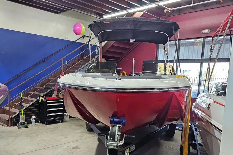Slide: The Image of 2023 Bayliner Element M19 boat in showroom, red hull, black canopy, indoor display. - 3