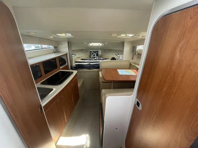 Slide: The Image of Interior of a 2004 Bayliner 285 boat, featuring a cozy cabin with kitchen and dining area. - 10