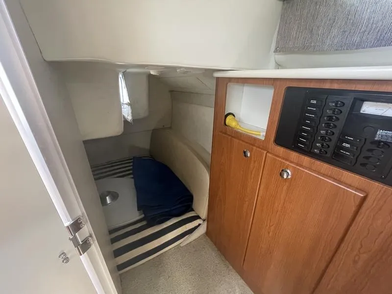 Slide: The Image of 2004 Bayliner 285 cabin interior with striped bedding and wooden cabinetry. - 13