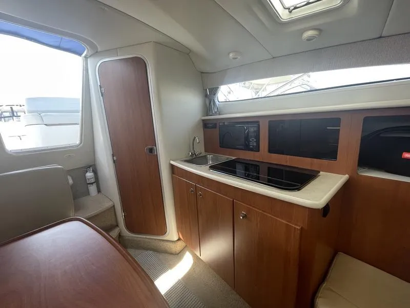Slide: The Image of Interior of 2004 Bayliner 285 boat featuring kitchenette with sink, stove, and microwave. - 16